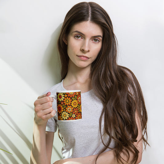 Retro 70s floral pattern ceramic mug featuring orange, yellow, and cream daisies on a dark brown background.