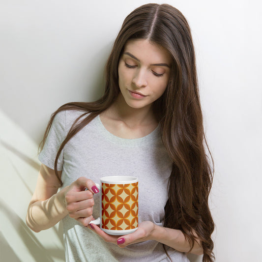 Ceramic coffee mug with a 1970s retro geometric pattern of interlocking orange and mustard petal shapes.