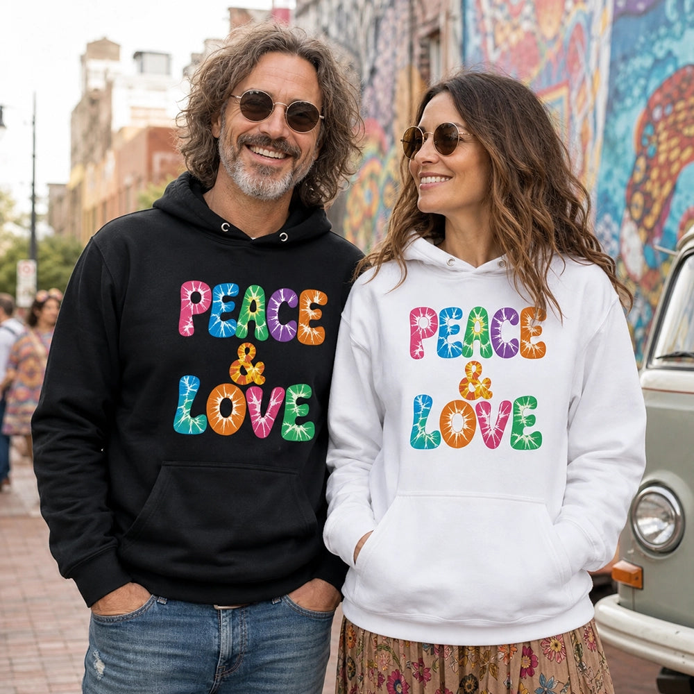 Retro tie-dye Peace and Love lettering printed on a black fleece hoodie pullover with vibrant 60s rainbow typography.