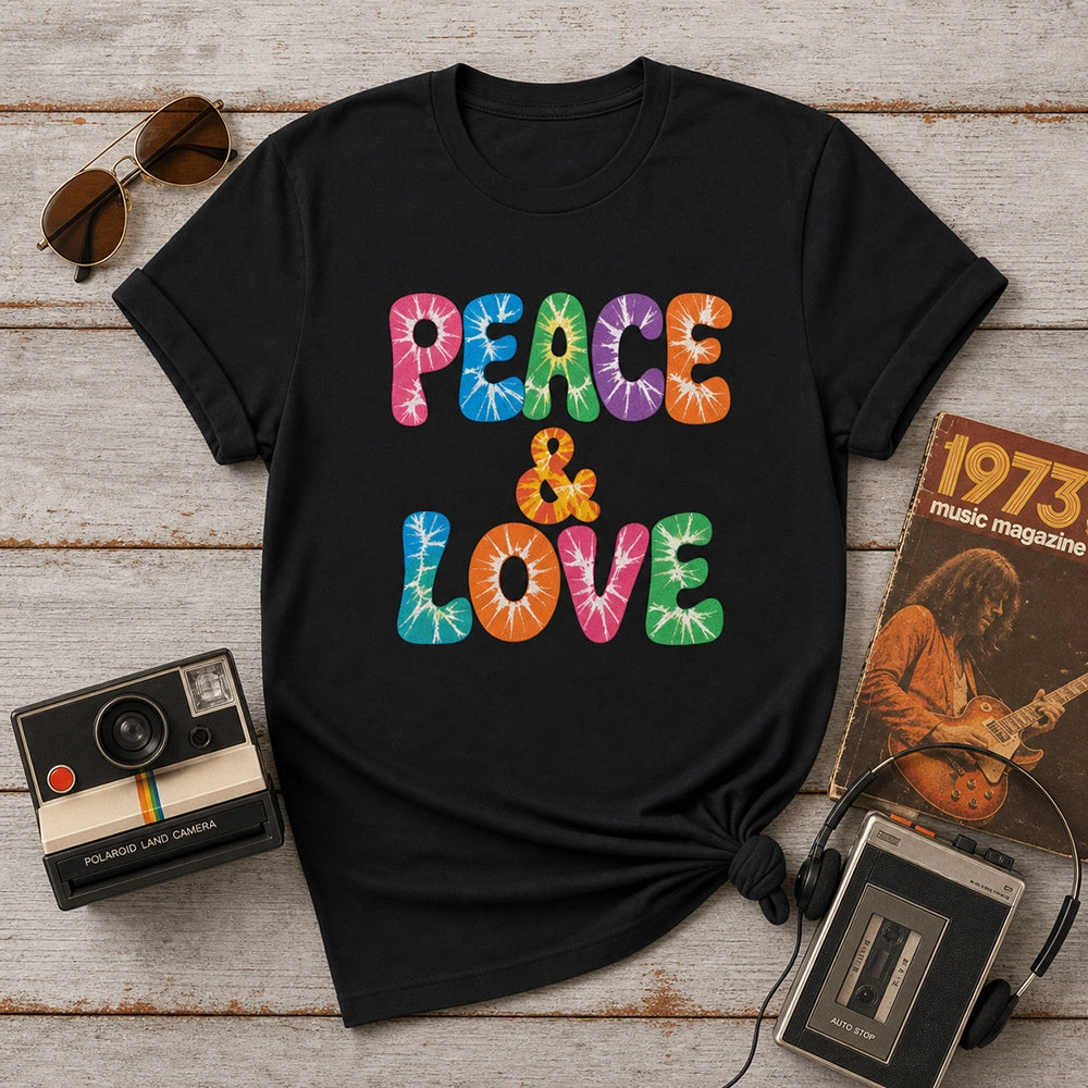 Retro tie-dye Peace and Love lettering printed on a classic black graphic t-shirt with vibrant 60s rainbow typography.
