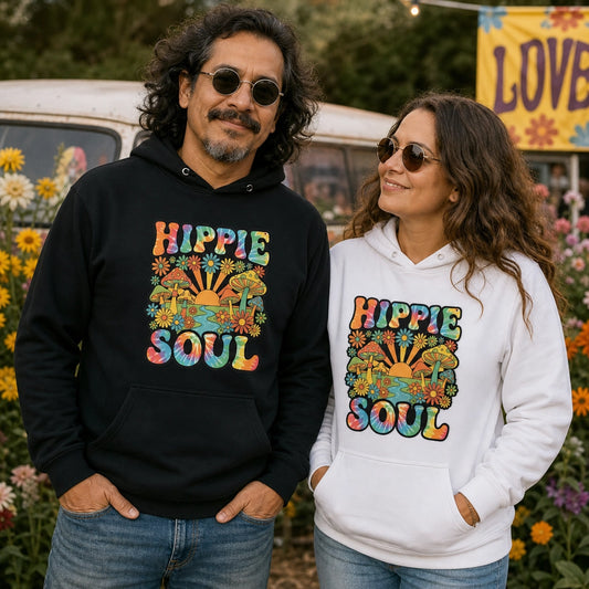 A man and a woman standing outdoors in front of flowers and a vintage vehicle, wearing matching hoodies. The man wears a black hoodie with a colorful retro psychedelic 'HIPPIE SOUL' graphic, and the woman wears a white hoodie with the same graphic.