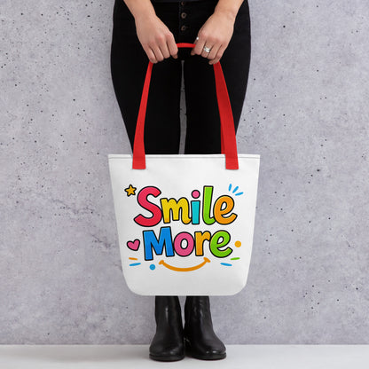 Colorful bubbly text reading "Smile More" with a yellow sun-smile and pink heart on a black canvas tote bag.