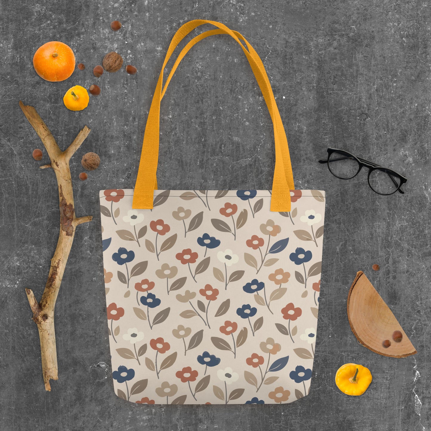 Canvas tote bag with a retro 70s mod flower pattern featuring large stylized blossoms in mustard yellow, burnt orange, and cream on a white background.