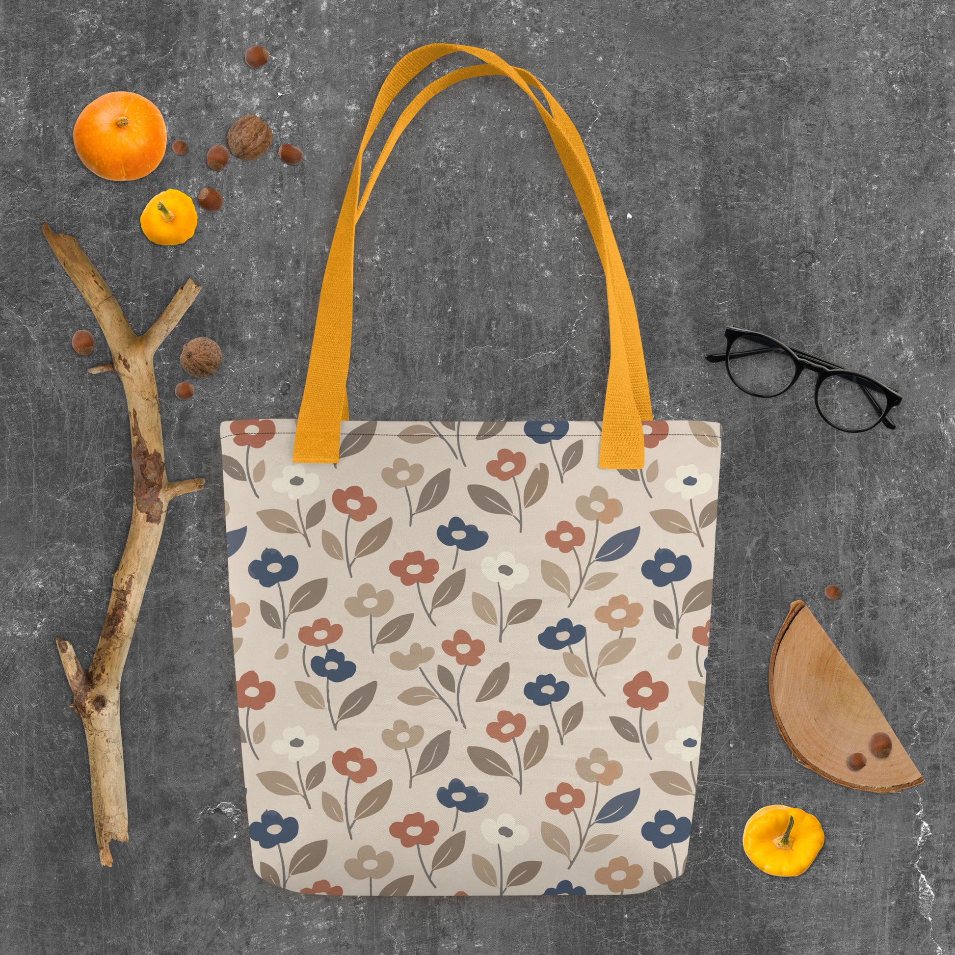 Canvas tote bag with a retro 70s mod flower pattern featuring large stylized blossoms in mustard yellow, burnt orange, and cream on a white background.