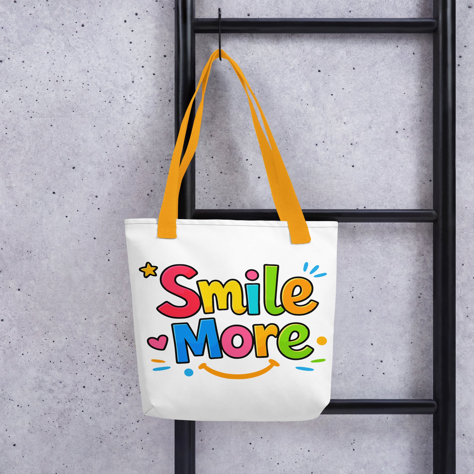 Colorful bubbly text reading "Smile More" with a yellow sun-smile and pink heart on a black canvas tote bag.