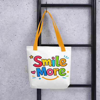 Colorful bubbly text reading "Smile More" with a yellow sun-smile and pink heart on a black canvas tote bag.