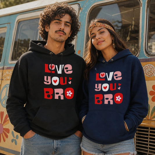 A man and a woman wearing matching graphic hoodies stand in front of a retro-style floral van. The man wears a black hoodie with pink, red, and white text reading 'LOVE YOU BRO' with a heart and flower motif.