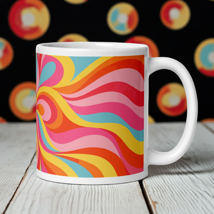 White glossy ceramic coffee mug featuring a continuous wraparound psychedelic swirl pattern in vibrant retro shades of orange, yellow, and pink.