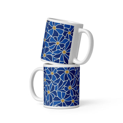 Ceramic coffee mug with a vibrant blue mosaic floral pattern and golden star centers by Far Out Goods.
