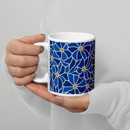 Ceramic coffee mug with a vibrant blue mosaic floral pattern and golden star centers by Far Out Goods.