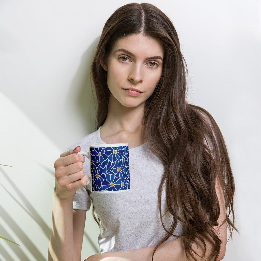 Ceramic coffee mug with a vibrant blue mosaic floral pattern and golden star centers by Far Out Goods.