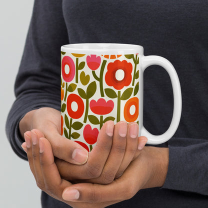 Retro 1970s flower power pattern ceramic mug featuring geometric orange, pink, and yellow flowers with green leaves