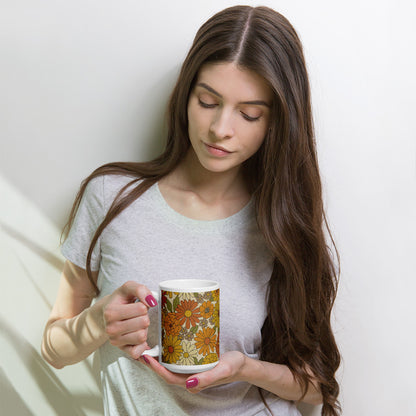 A ceramic coffee mug featuring a seamless retro groovy floral pattern with warm orange, yellow, and cream daisy blooms.